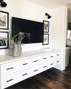 a large white dresser with black and white pictures on the wall next to an entertainment center