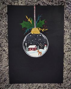 a christmas ornament hanging from a black piece of paper on top of carpet