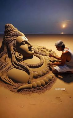 a man sitting on top of a sandy beach next to a sand sculpture