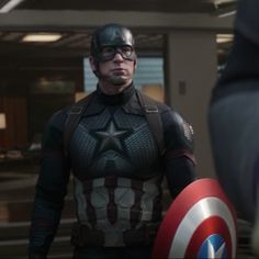 captain america the winter soldier is standing next to another man in an office building with his hands on his hips