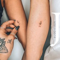 two women with matching tattoos on their legs and one is holding her hand up to the other