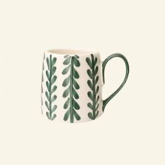 a green and white mug with leaves on it