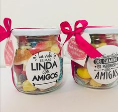 two glass jars filled with candies on top of a white table next to each other