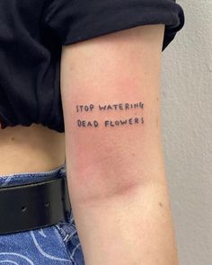 a woman with a tattoo on her arm that says stop watering dead flowers