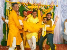 four men in yellow outfits are posing for the camera with their hands up and smiling