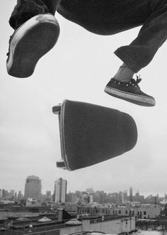 a man flying through the air while riding on top of a skateboard in front of a city skyline