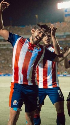 two soccer players are congratulating each other at the end of a game with their arms in the air