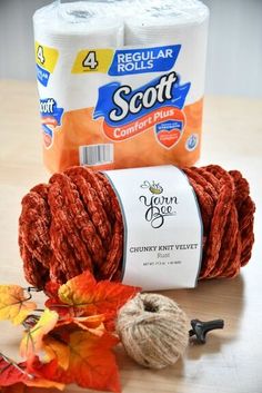 two rolls of scott comfort plus yarn sitting on top of a table next to autumn leaves