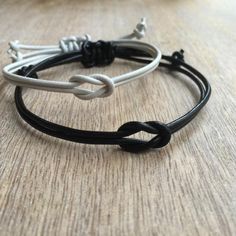 two black and white leather bracelets sitting on top of a wooden table