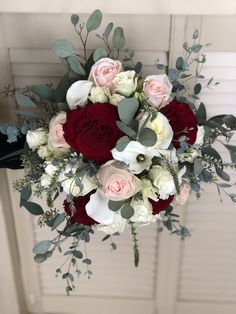 a bouquet of roses and greenery is hanging on the door handle in front of a white door