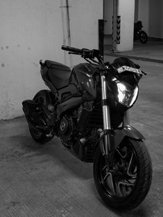 a black and white photo of a motorcycle parked in a parking garage next to a wall