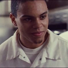 a close up of a person wearing a white shirt and looking at the camera with a serious look on his face