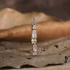 a diamond ring sitting on top of a leaf covered ground next to a wooden object