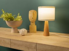 a wooden table topped with a lamp next to a plant