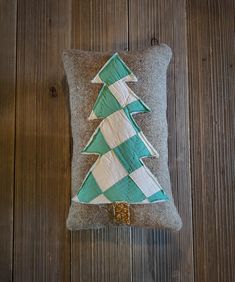 a green and white christmas tree pillow sitting on top of a wooden floor next to a wall