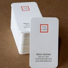 two business cards sitting side by side on a brown surface with red and white squares