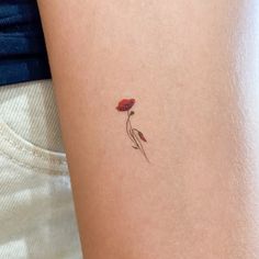 a small red flower on the back of a woman's left arm and leg