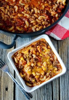 a casserole dish filled with pasta and ground beef in a red and white checkered cloth