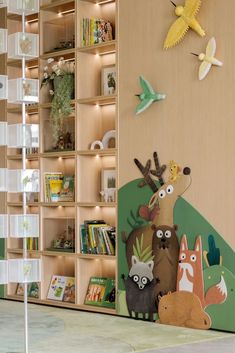 the children's room is decorated with wooden shelves and colorful animals on them, along with bookshelves