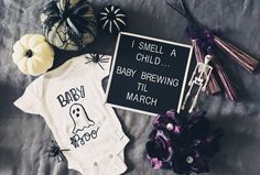 a baby's bodysuit and other halloween items on a bed with a sign that says i smell a child, baby brewing til march