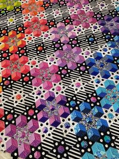 a multicolored quilt is laying on the ground with black and white polka dots