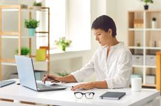 a woman sitting at a desk using a laptop computer