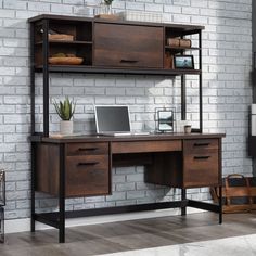 a desk with a laptop on it in front of a white brick wall and wooden shelves