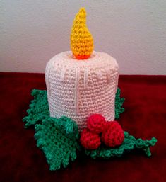 a crocheted birthday cake sitting on top of a red table next to a white wall