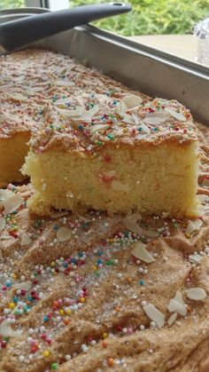 a cake with sprinkles on it sitting in a pan next to a window