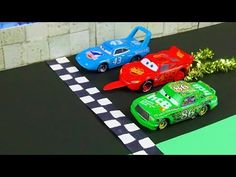 two toy cars on a race track with green and red one next to each other