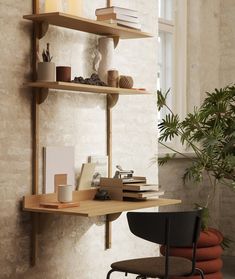 a desk with some books on it next to a chair and potted plant in the corner