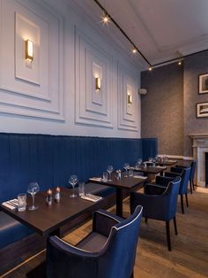 an empty restaurant with blue booths and wooden tables set up for two people to eat