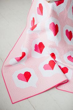 a pink and white quilt with hearts on it