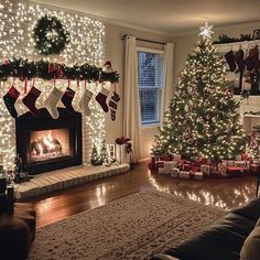 a living room decorated for christmas with lights and stockings on the fireplace mantels