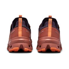 a pair of brown and orange shoes on a white background with the soles off