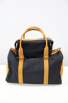 a black and yellow duffel bag sitting on top of a white table