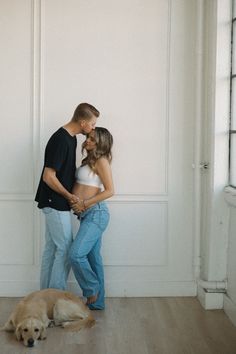 a man and woman standing next to each other with a dog laying on the floor