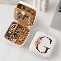 an open jewelry box sitting on top of a white table next to a laptop computer