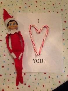 an elf with a candy cane next to a valentine's card that says i love you