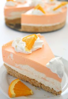 a slice of orange cheesecake on a white plate next to an orange and whipped cream topping