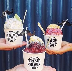 three ice cream sundaes with fake mustaches on their heads are being held by two hands