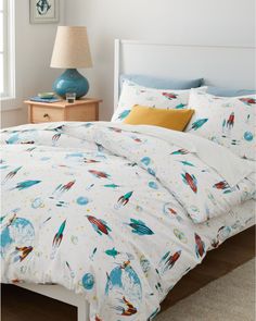 the comforter is made up with colorful rockets and planets on white bed linens