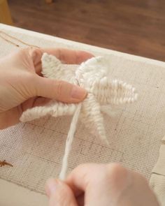 someone is working on something that looks like a star ornament in white yarn