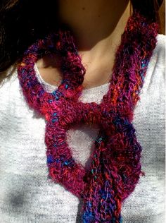 a woman wearing a purple and red knitted scarf with a loop around her neck