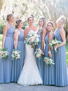 a group of women standing next to each other holding bouquets in their hands and posing for the camera