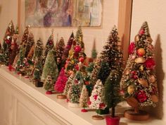 there are many small christmas trees on the mantle