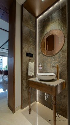 a bathroom sink sitting under a mirror next to a wooden cabinet and wall mounted faucet