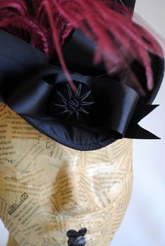 This gorgeous victorian mini top hat will compliment your victorian style gown in the most elegant way! It is covered with black satin with a discreet shine and embellished with black velvet ribbon along with black grosgrain ribbon, placed in an asymmetrical sculptural bow at one side front. A beautiful round velvet button and a glorious burgundy ostrich plum finish off this unique victorian inspired topper! Measurements : height 3.5 inches( 9 cm ),without the feather front to back 7.5 inches ( Elegant Halloween Fascinator, Elegant Black Costume Hat, Elegant Black Hat For Costume, Elegant Fitted Halloween Costume Hats And Headpieces, Elegant Black Costume Top Hat, Elegant Black Top Hat For Costume, Elegant Black Top Hat For Halloween, Vintage Top Hat With Curved Brim For Costume Party, Vintage Black Fascinator For Costume Party