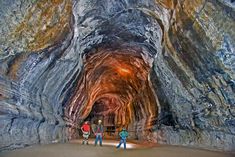 three people are standing in the middle of a tunnel with light coming from it's sides