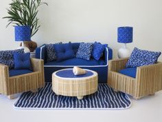 a living room with blue and white furniture on top of a rug next to a potted plant